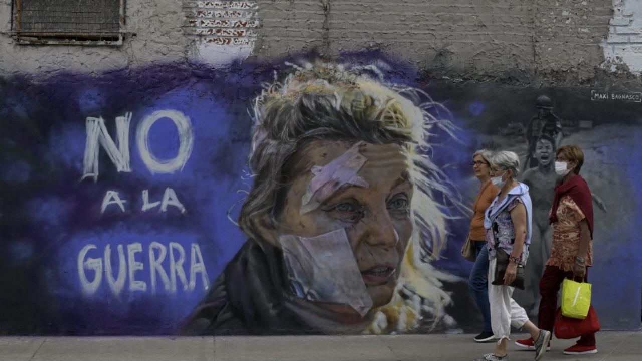 Women walk past the mural 'No to war' by muralist Maximiliano Bagnasco in Buenos Aires on March 5, 2022. Bagnasco painted this mural against the war inspired by two iconic images -- the portrait of Helena (C), a 53-year-old teacher standing outside a hospital after the bombing of the eastern Ukrainian town of Chuguiv on February 24, 2022, as Russian armed forces invaded Ukraine, taken by AFP Greek photojournalist Aris Messinis, and Kim Phuc Phan Thi, also known as 'Napalm Girl', the iconic 1972 Vietnam War photograph taken by Nick Ut of AP. Photo: AFP